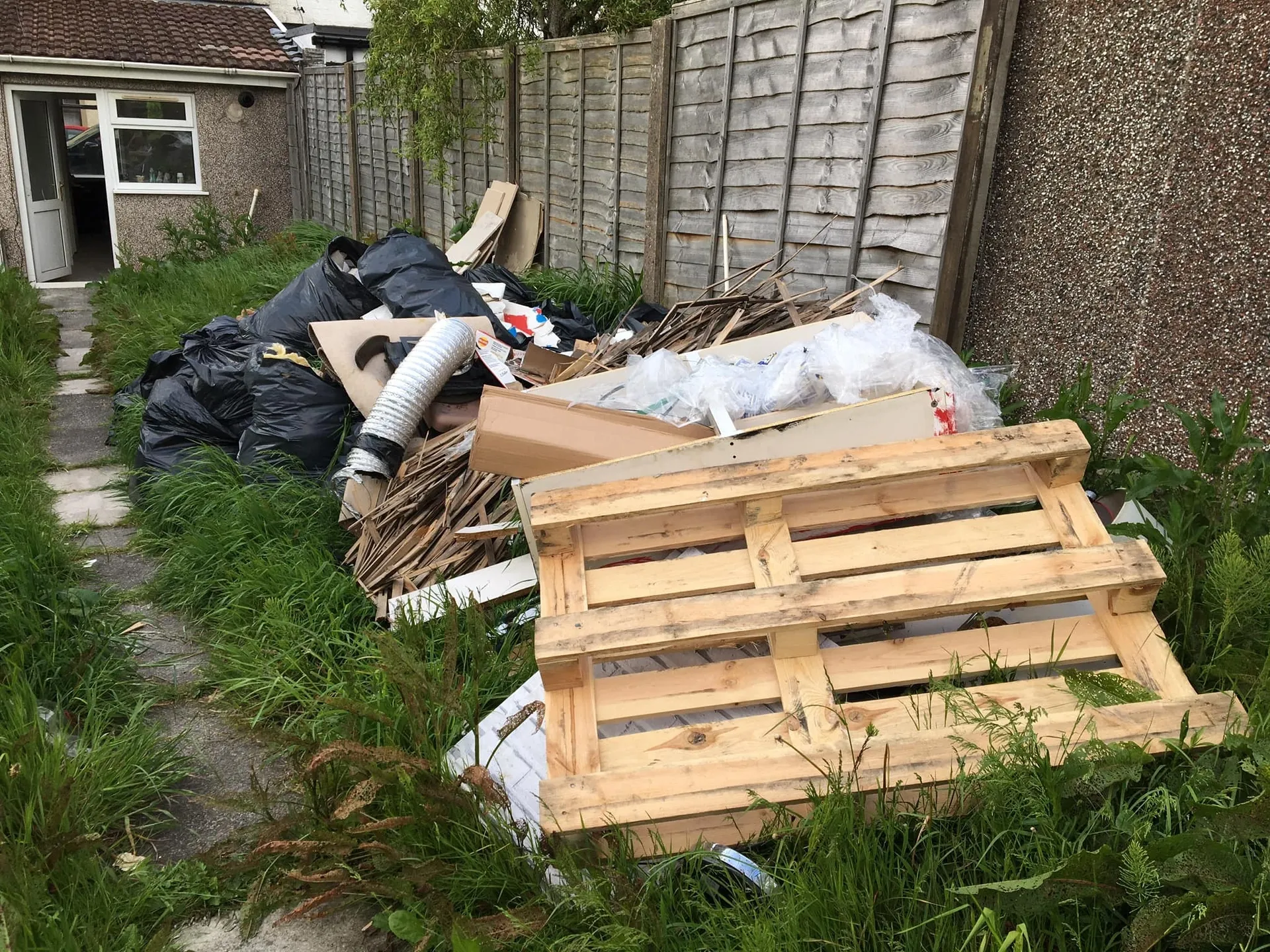 a photo of a garden full of junk, one large wooden pallet in Neath, Port Talbot, and Swansea