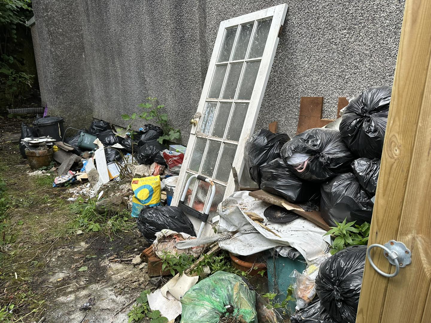 a photo of a wooden door with glass panels with junk surrounding in Neath, Port Talbot, And Swansea