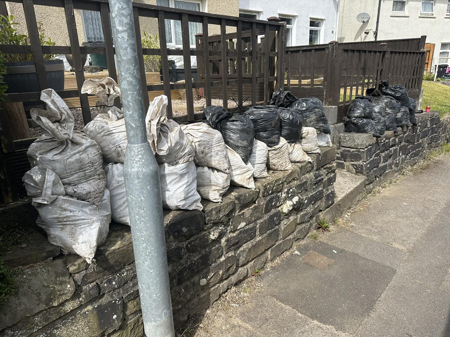 Photo of garden debris bagged up on the wall ready for collection